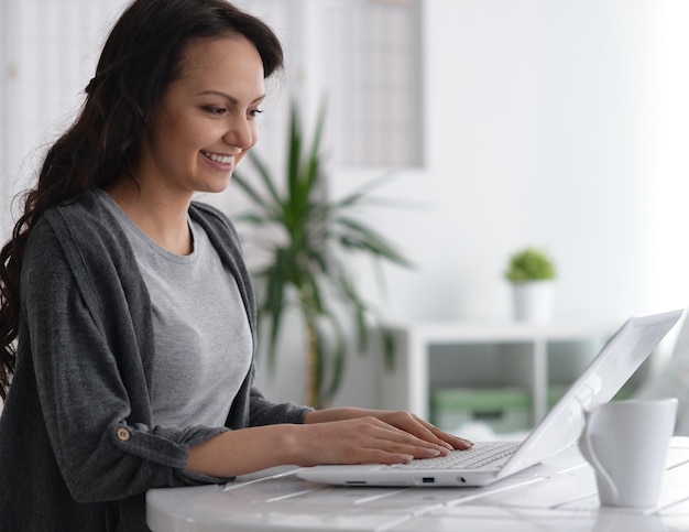 Porträt einer schönen jungen Frau, die modernen Laptop verwendet