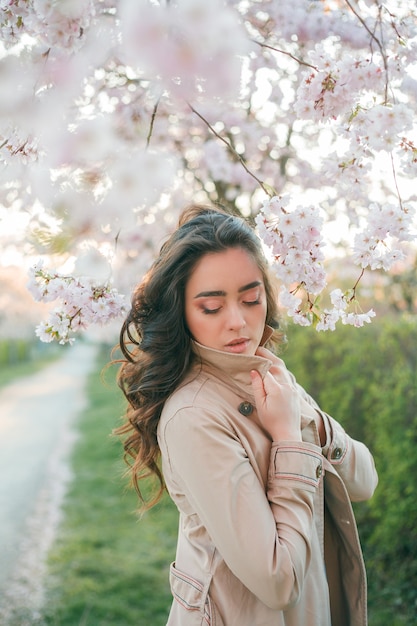 Porträt einer schönen jungen Frau in der blühenden Sakura bei Sonnenuntergang