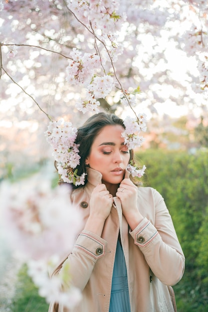 Porträt einer schönen jungen Frau in der blühenden Sakura bei Sonnenuntergang