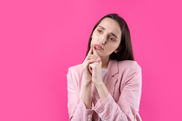 Porträt einer schönen jungen Frau in rosa Jacke, die isoliert auf rotem Hintergrund denkt