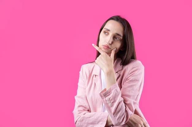 Porträt einer schönen jungen Frau in rosa Jacke, die isoliert auf rotem Hintergrund denkt