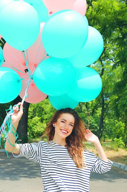 Porträt einer schönen jungen Frau mit bunten Luftballons im Park