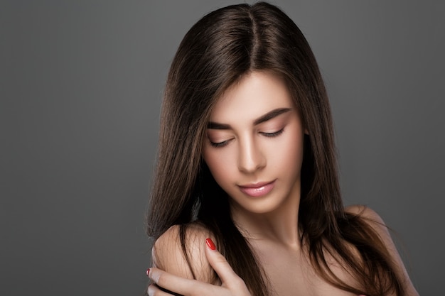 Porträt einer schönen jungen Frau mit perfekter Haut und natürlichem Make-up auf grauem Hintergrund