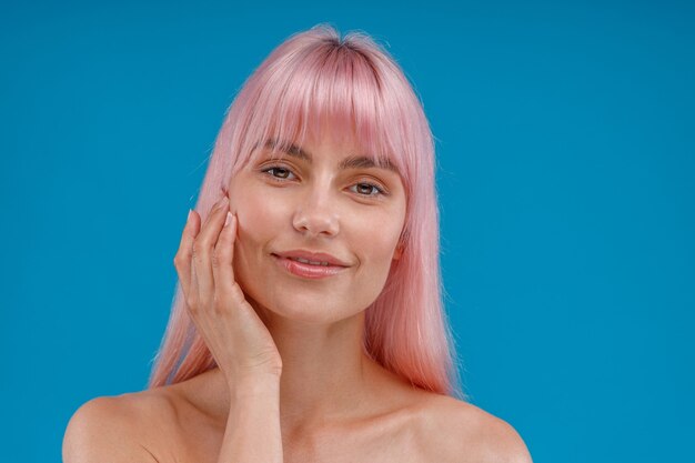 Porträt einer schönen jungen Frau mit rosa Haaren und perfekter Haut, die isoliert in die Kamera schaut