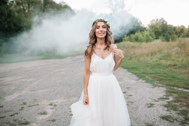 Porträt einer schönen jungen sexy Mädchenbraut mit Blumen in ihrem Haar schauen in einem weißen Kleid attraktiv