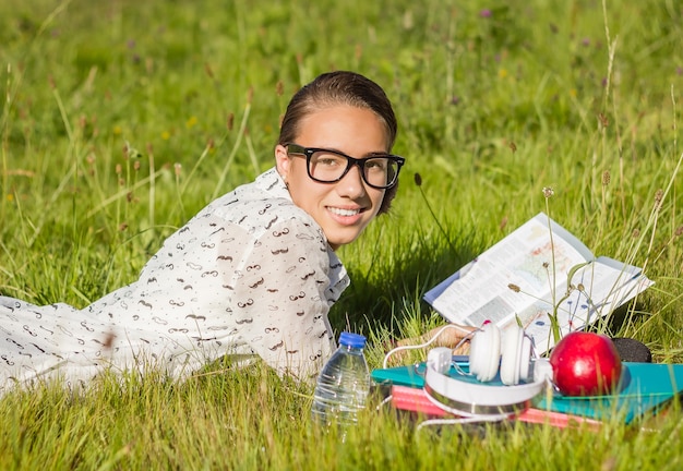 Porträt einer schönen jungen Studentin, die ein Buch im Schulpark liest