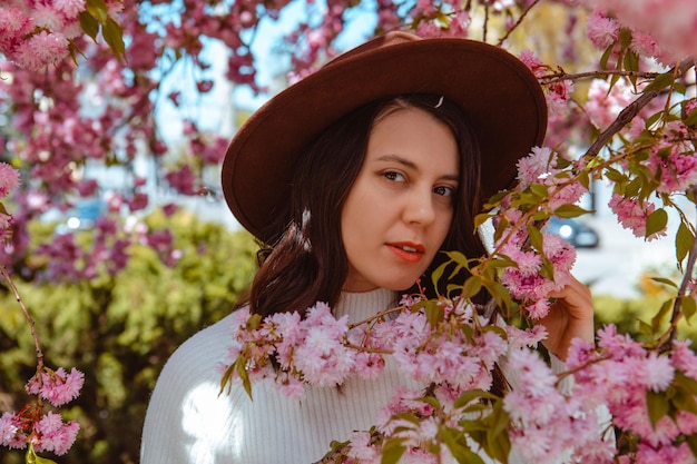 Porträt einer schönen kaukasischen Frau mit blühenden Sakura-Kirschbäumen, Kopienraum