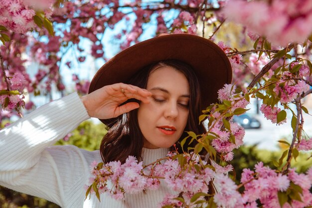 Porträt einer schönen kaukasischen Frau mit blühenden Sakura-Kirschbäumen, Kopienraum