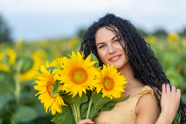 Porträt einer schönen lächelnden dunkelhaarigen Frau mit Strauß Sonnenblumen