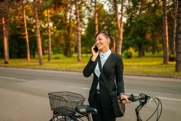 Porträt einer schönen lächelnden Geschäftsfrau mit einem Fahrrad sprechend am Telefon.