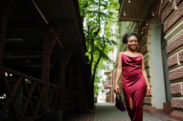 Porträt einer schönen natürlichen jungen afrikanischen Frau mit Afrohaar. Schwarzes Modell im roten Seidenkleid.