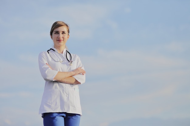 Porträt einer schönen Ärztin oder Krankenschwester gegen blauen Himmel mit Wolken