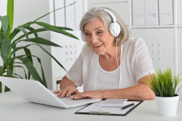 Porträt einer schönen Seniorin, die zu Hause einen Laptop verwendet