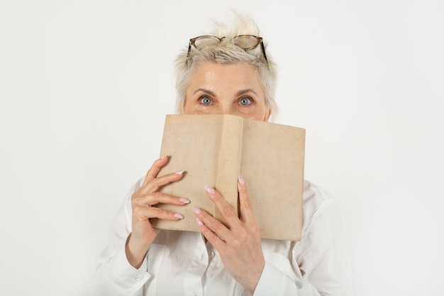 Porträt einer schönen stilvollen Frau in Gläsern mit einem überraschten Gesicht mit einem Buch