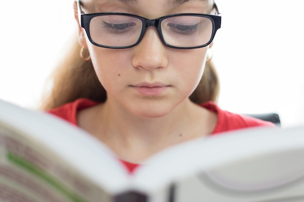 Porträt einer schönen und jungen Studentin, die ein Buch in Nahaufnahme auf weißem Hintergrund liest
