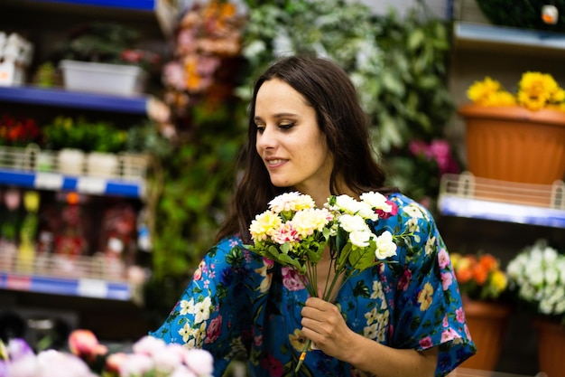 Porträt einer Schönheitsfrau, die einen Eimer Blumen in einem Blumenladen auswählt und hält