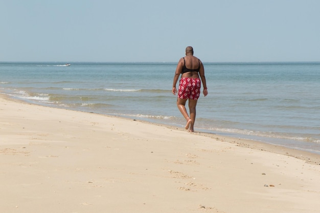 Porträt einer schwarzen Frau, die barfuß am Strand spazieren geht