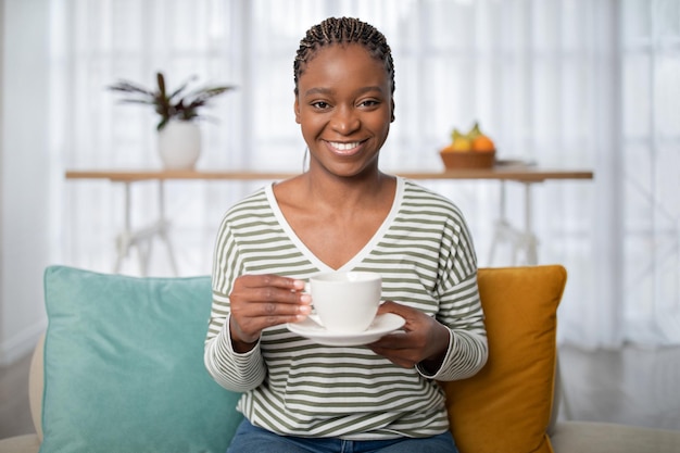 Porträt einer schwarzen Frau, die zu Hause frischen aromatischen Kaffee genießt