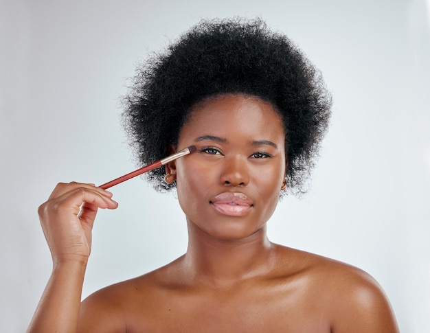 Porträt einer schwarzen Frau und Make-up-Pinsel auf den Augen für die Hautpflege vor weißem Studiohintergrund. Gesicht einer afrikanischen Frau, die Augenpflegeprodukte oder Wimpern zur Gesichtsbehandlung aufträgt