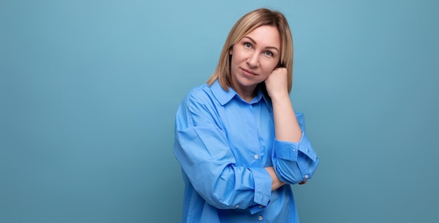 Porträt einer selbstbewussten, ruhigen europäischen blonden Frau in einem Hemd auf blauem Hintergrund mit Copyspace