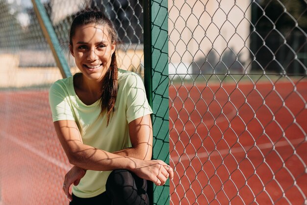 Porträt einer Sportlerin, die in der Nähe eines Maschendrahtzauns steht