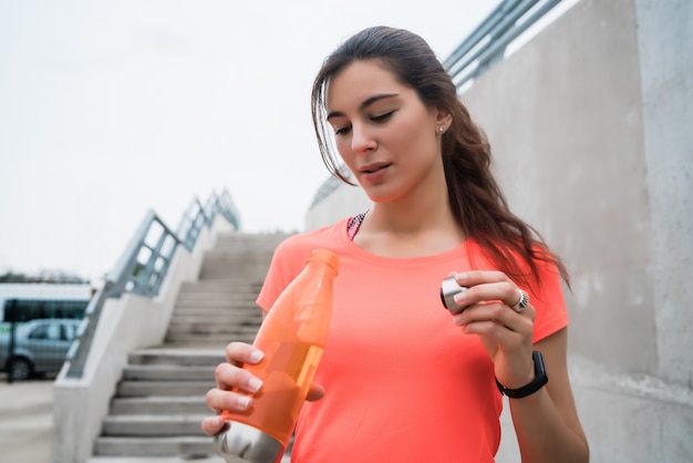 Porträt einer sportlichen Frau, die Wasser nach dem Training trinkt. Sport- und Gesundheitskonzept.