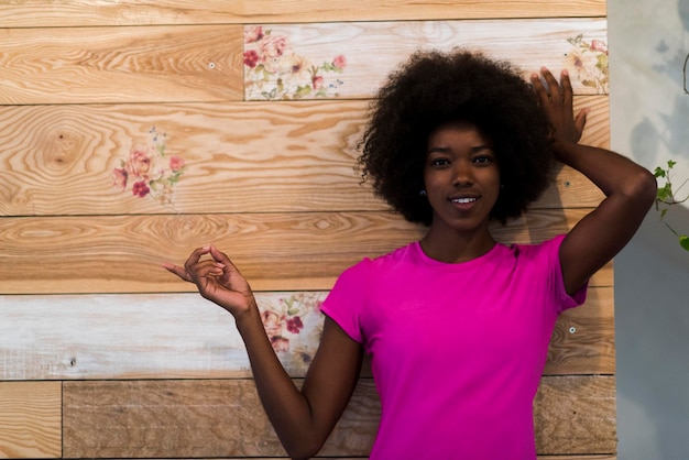 Porträt einer süßen afroamerikanischen Frau mit Afro-Frisur, während sie vor altem Retro-Holzhintergrund posiert