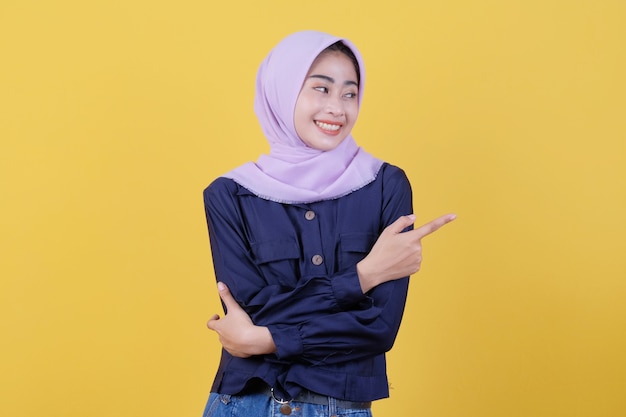 Porträt einer süßen Frau, die in legerem Tuch mit Hijab auf isoliertem gelbem Hintergrund nach oben zeigt