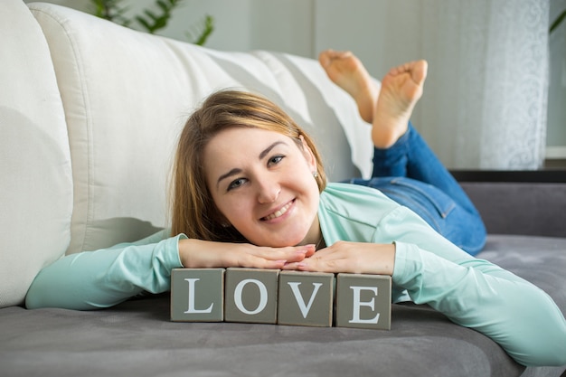 Porträt einer süßen Frau, die mit dekorativem Wort "Liebe" posiert