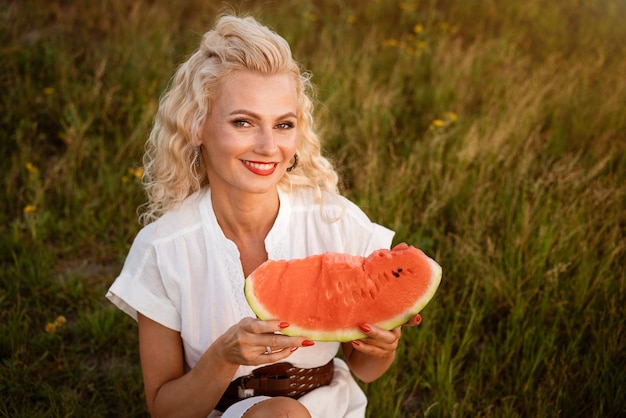 Porträt einer süßen Frau mit einem Stück Wassermelone in der Hand in der Natur fröhliches Mädchen, das reife ...