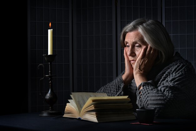 Porträt einer traurigen älteren Frau mit Buch