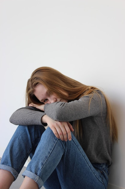 Porträt einer traurigen Frau, die an der Wand sitzt