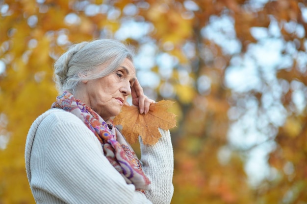 Porträt einer traurigen Seniorin im Herbstpark