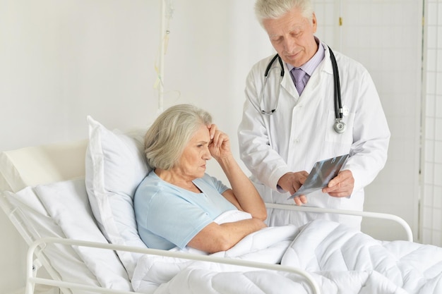 Porträt einer traurigen Seniorin im Krankenhaus mit fürsorglichem Arzt