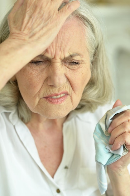 Porträt einer traurigen Seniorin mit Kopfschmerzen zu Hause hautnah