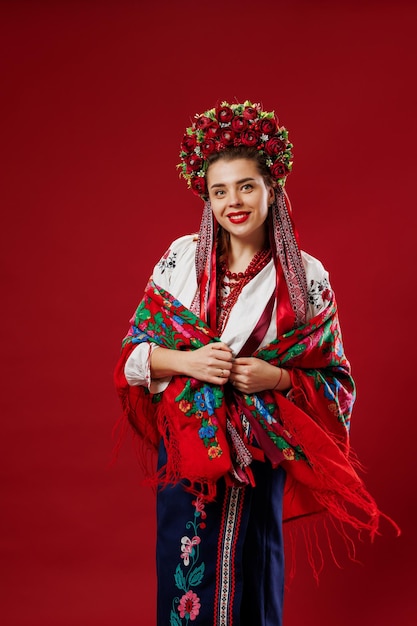 Porträt einer ukrainischen Frau in traditioneller ethnischer Kleidung und rotem Blumenkranz auf viva magenta Studiohintergrund Ukrainische nationale bestickte Kleidung rufen Vyshyvanka an. Beten Sie für die Ukraine