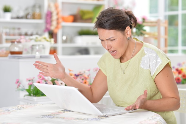 Porträt einer verärgerten jungen Frau, die einen Laptop verwendet