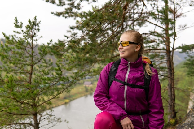 Porträt einer Wandererin, die auf einer Klippe über einem Flusstal sitzt