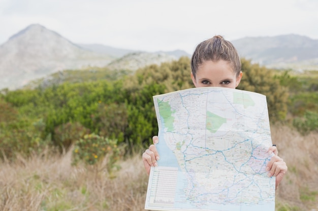 Porträt einer wandernden jungen Frau, die Karte hält