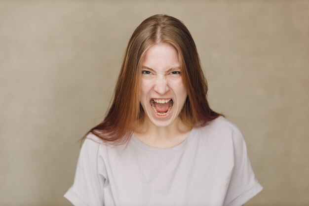 Foto porträt einer weinenden jungen kaukasischen frau, die gegen beige hintergrund in die kamera schaut