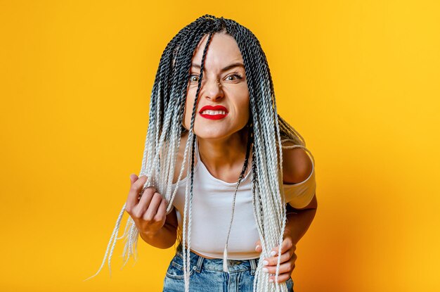 Foto porträt einer wütenden frau mit dreadlocks hände, die dreadlocks halten, die sich nach unten lehnen, um zu schauen