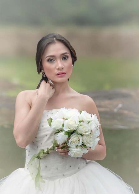Porträt einer wunderschönen Braut mit einem Blumenstrauß weißer Rosen