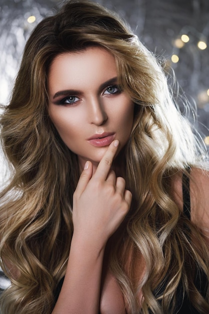 Porträt einer wunderschönen Frau mit schönem lockigem Haar und professionellem Make-up im Studio