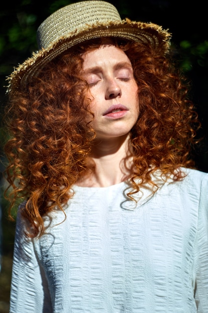 Porträt einer zarten kaukasischen Rothaarigen mit lockigem, gewelltem Haar, die mit geschlossenen Augen posiert