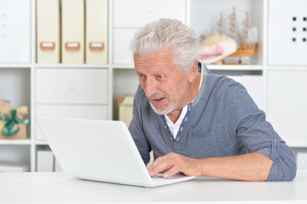 Porträt eines älteren Mannes mit Laptop zu Hause