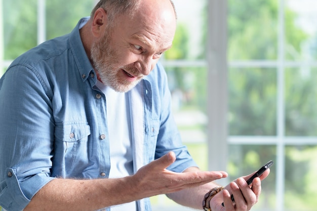 Porträt eines älteren Mannes mit Telefon zu Hause