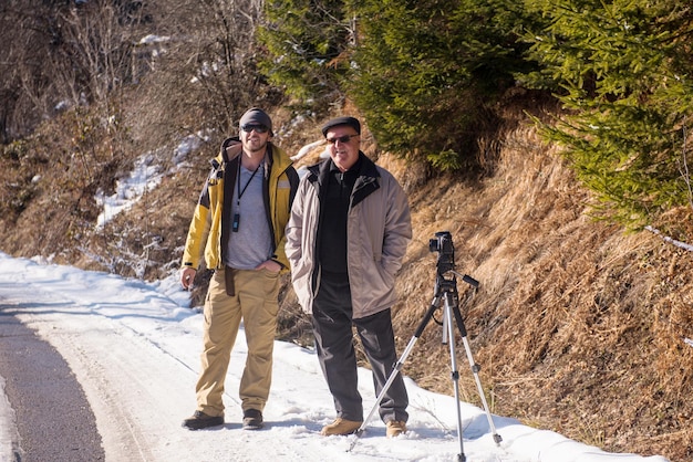 Porträt eines älteren und jüngeren Fotografen beim Fotografieren des Winterwaldes mit Digitalkamera an der Bergstraße