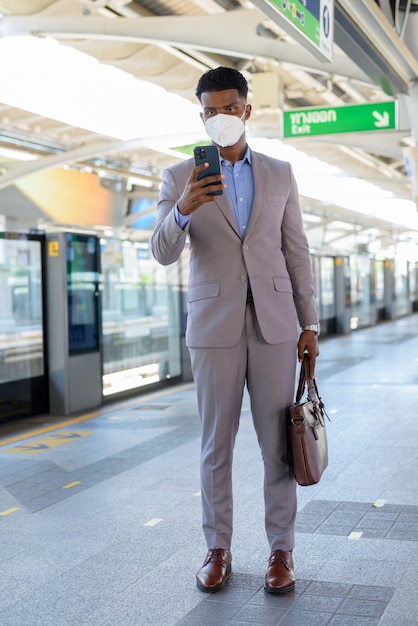 Porträt eines afrikanischen Geschäftsmannes am Bahnsteig mit Gesichtsmaske