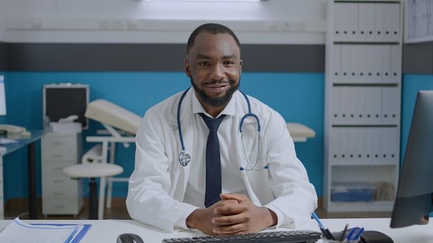 Porträt eines afroamerikanischen Arztes, der medizinische Dokumente analysiert, die im Krankenbericht im Krankenhausbüro arbeiten. Fachtherapeut, der eine medikamentöse Behandlung entwickelt. Medizinkonzept