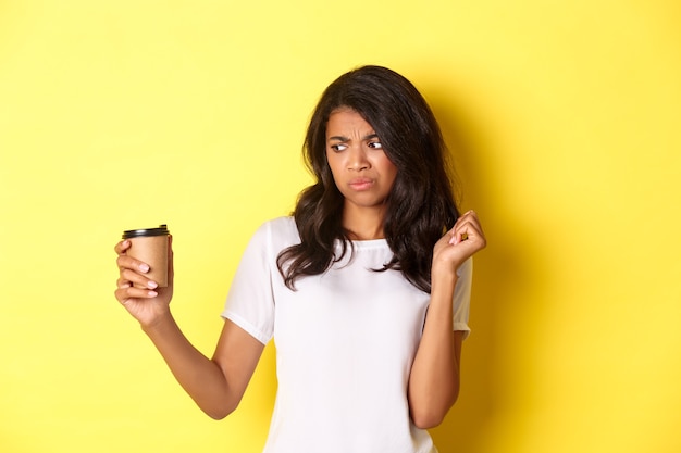Porträt eines afroamerikanischen Mädchens, das enttäuscht auf die Tasse schaut, mag keinen schlechten Kaffee, der über Schreien steht ...